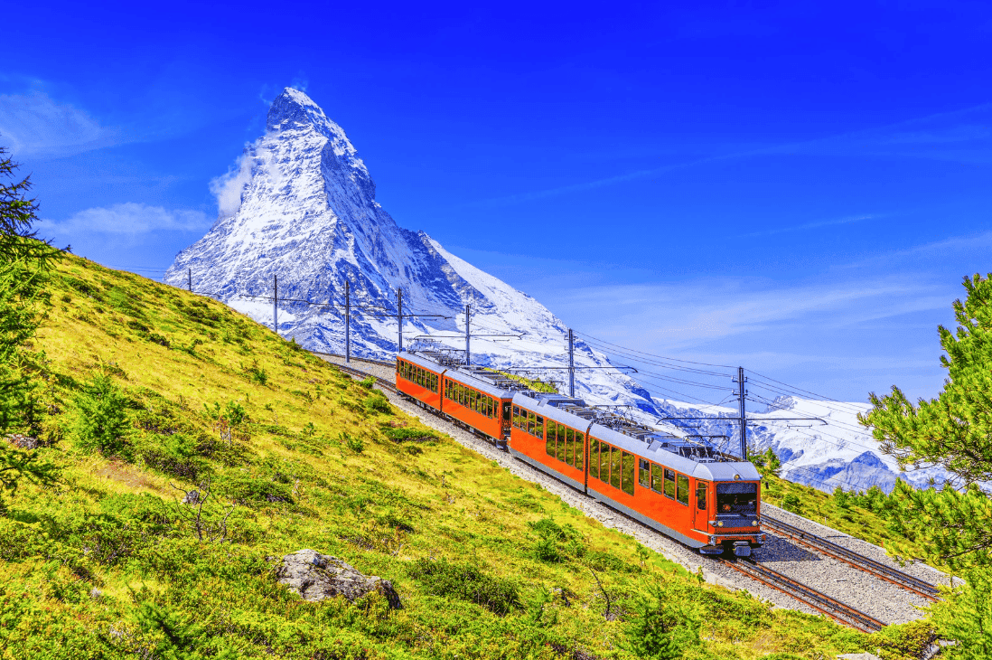 Bergbahn in grüner Landschaft mit Blick auf das Matterhorn