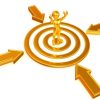 Goldene Figur auf Zielscheibe mit Pfeilen, symbolisiert Zielerreichung.